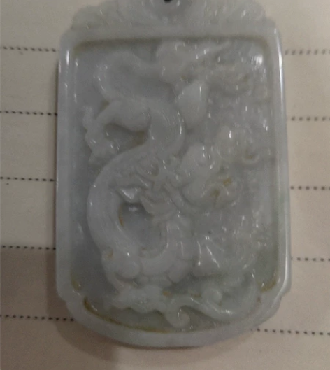 一块精美玉雕龙牌，似是翡翠玉，下端有点点淡...